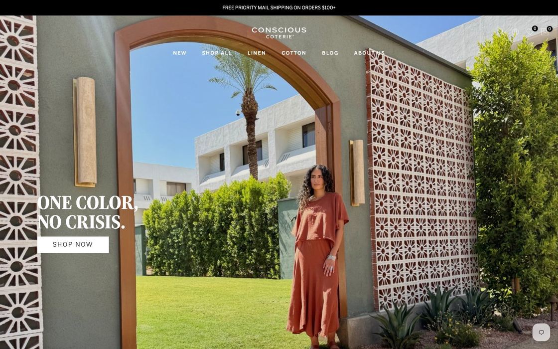 Conscious Coterie online store: woman in a rust linen dress in a sunlit Spanish-style courtyard